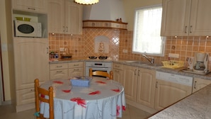 A kitchen with wooden cabinets, a microwave, a stove, and a coffee maker.