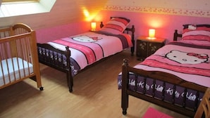 A bedroom with two beds, each with Hello Kitty bedding, a wooden crib, and a skylight.