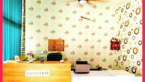 A reception desk with a 'RECEPTION' sign, a laptop, a water bottle, and a red bag on the counter. - Hotel The NV Grand Palace Vrindavan (Vrindavan)