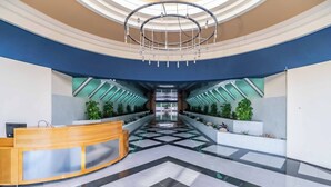 Un hall d’entrée moderne avec un comptoir d’accueil, un sol à motifs géométriques et un lustre central.