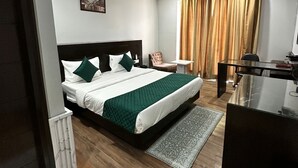 A modern hotel room with a large bed, a desk, and a chair. - VR RESIDENCY (Gurugram)
