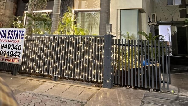 A modern two-story residential building with a gated entrance, palm trees, and a sign for 'Dinda Estate'. - VR RESIDENCY (Gurugram)
