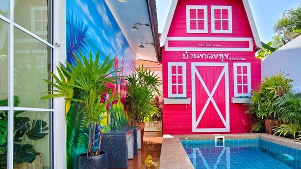 A vibrant red building with a large white X on the door, surrounded by a swimming pool and potted plants. - Canary Pool Villa Bangsaen (Chonburi)