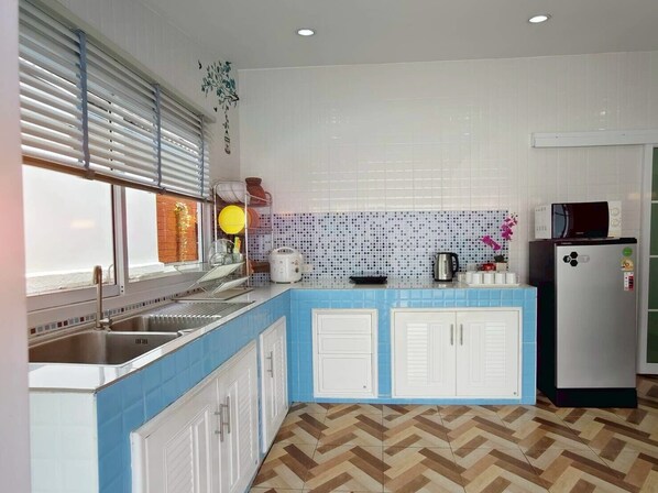 A kitchen with a blue countertop, white cabinets, a microwave, and a refrigerator. - Canary Pool Villa Bangsaen (Chonburi)