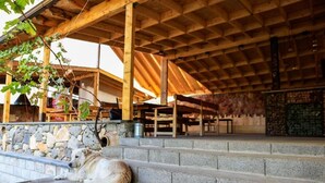 A rustic wooden structure with a stone wall and steps leading up to a covered area. - Areni Wine Art (Areni)