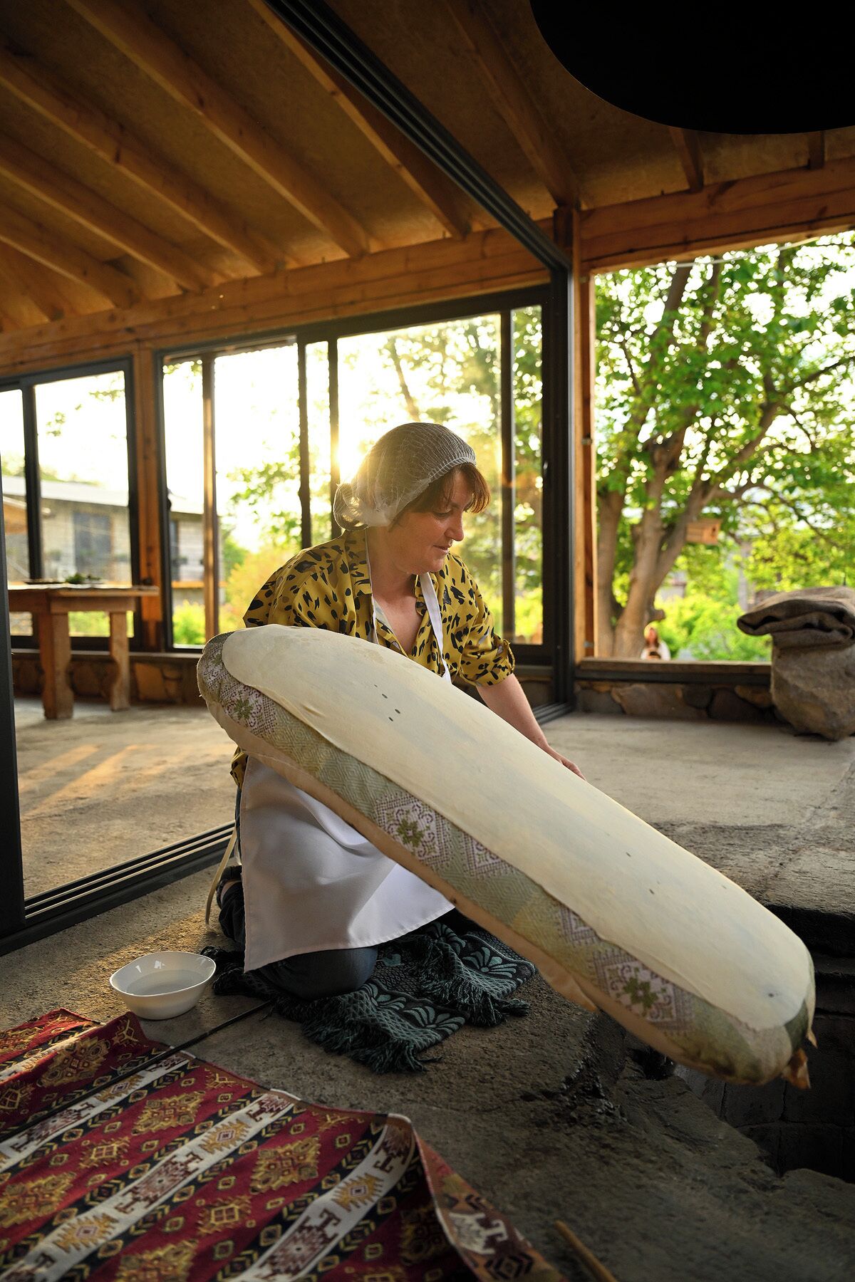 A person in a covered outdoor area with wooden beams, holding a large white object.