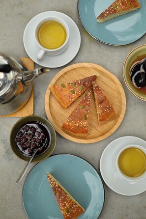 A table setting with a teapot, cups, and a wooden board with bread slices.