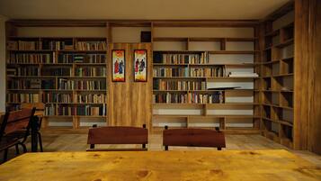 Una biblioteca con estanterías de madera, dos bancos y una mesa.