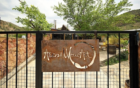 A rustic metal gate with a sign reading "Arni Wine Art".