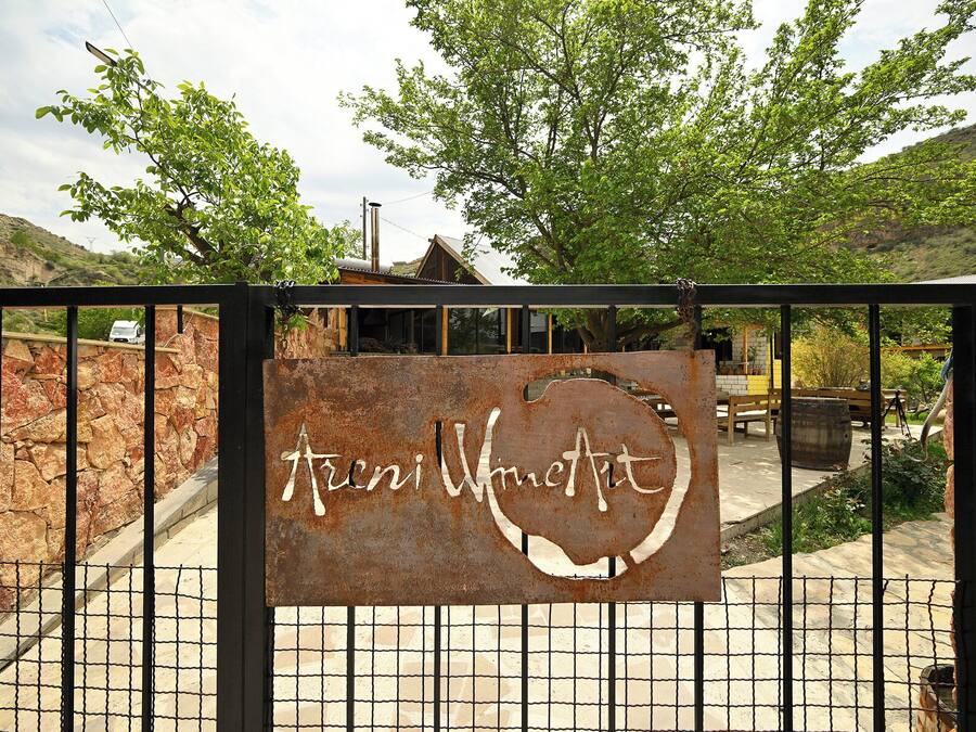 A rustic metal gate with a sign reading "Arni Wine Art".
