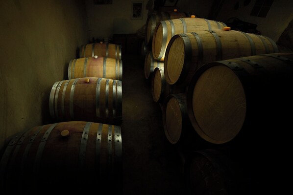 Several wooden barrels stacked in a dimly lit room. - Areni Wine Art (Areni)