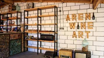 Un interior rústico con estantes de madera que exhiben varios objetos, una pared de ladrillo con el rótulo 'AREN WINE ART' y radios antiguas.