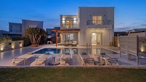 A modern two-story house with a swimming pool, outdoor seating, and a pergola.
