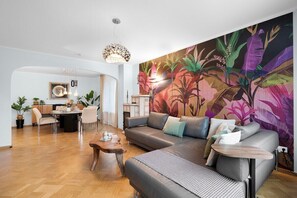 A modern living room with a large sofa, a coffee table, and a dining area with a table and chairs.