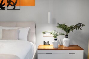 Una camera da letto ordinata con un letto, comodini e due piante in vaso.