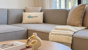 A modern living room with a beige sofa, a decorative vase, and a magazine on a coffee table. - HiGuests - La Rive Classy 2BR & Balcony (Dubai)