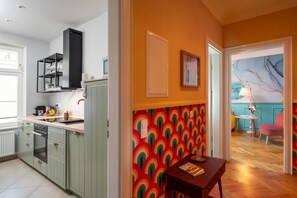 A kitchen with a built-in oven, a black range hood, and a countertop with a sink.