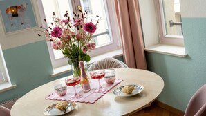 A round table with a pink placemat, a vase with flowers, and three glasses of red wine.