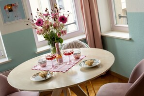 A round table with a pink placemat, a vase with flowers, and three glasses of red wine.
