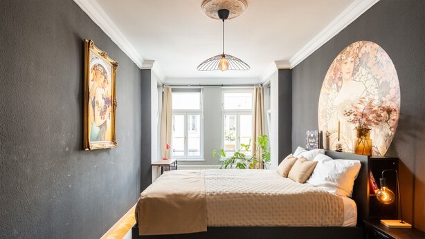 A bedroom with a bed, bedside table, and a large painting on the wall.