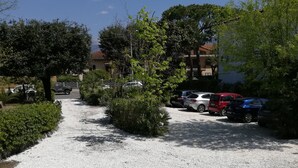 Uma trilha de cascalho que leva a um estacionamento com vários carros.