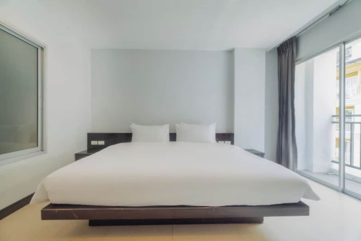 Une chambre d’hôtel moderne avec un grand lit, une table de chevet et une fenêtre avec des rideaux.