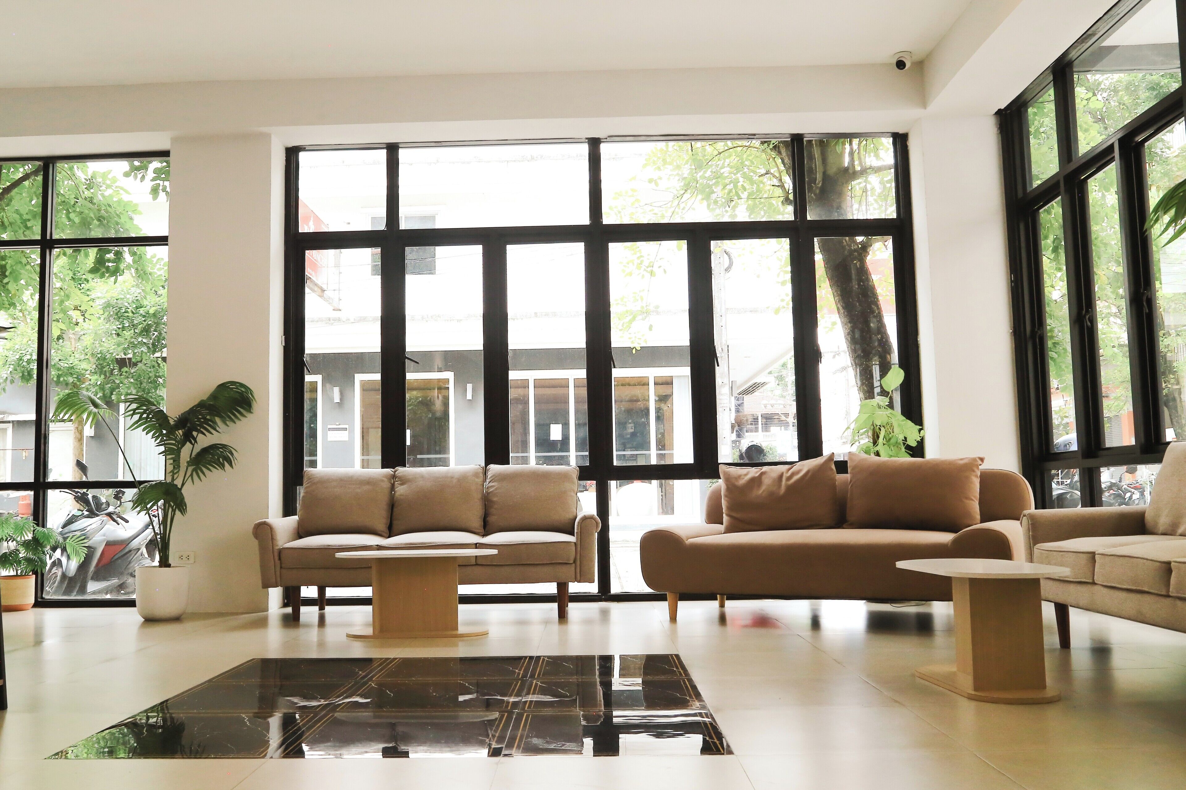 Uma sala de estar moderna com janelas amplas, dois sofás, uma mesa de centro e um vaso de planta.