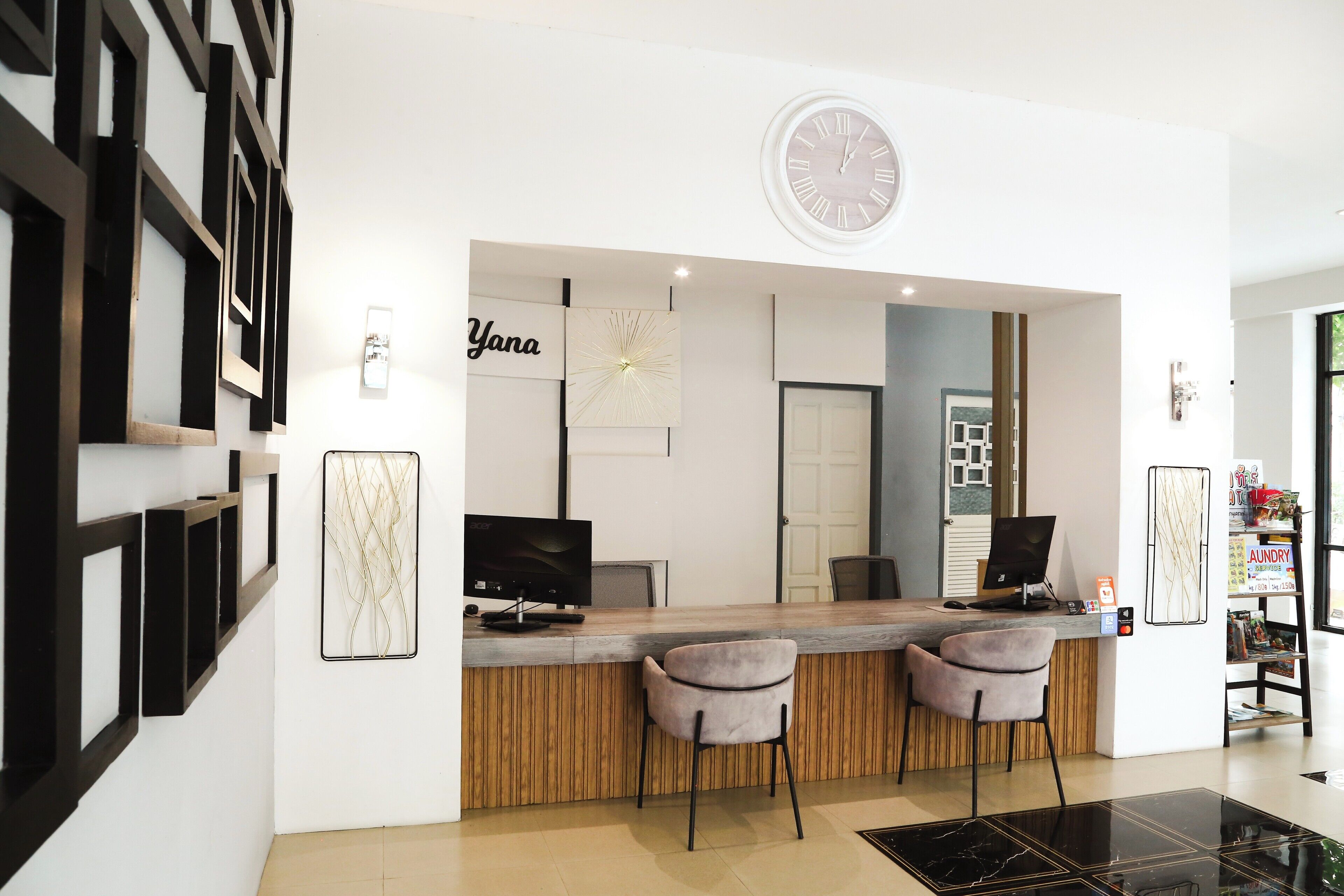 A reception area with a wooden counter, two chairs, a clock, and a wall-mounted sign.