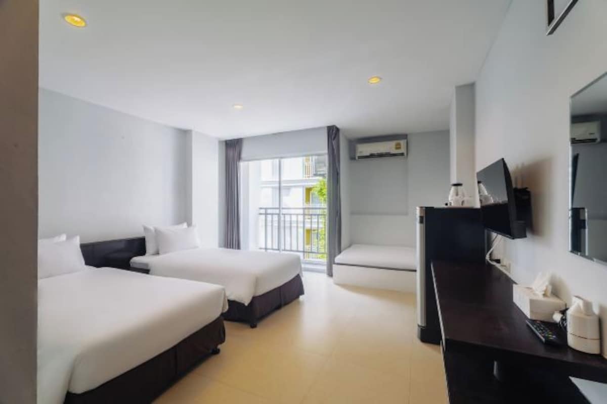 Une chambre d’hôtel avec deux lits, un bureau, une télévision et un balcon avec vue.