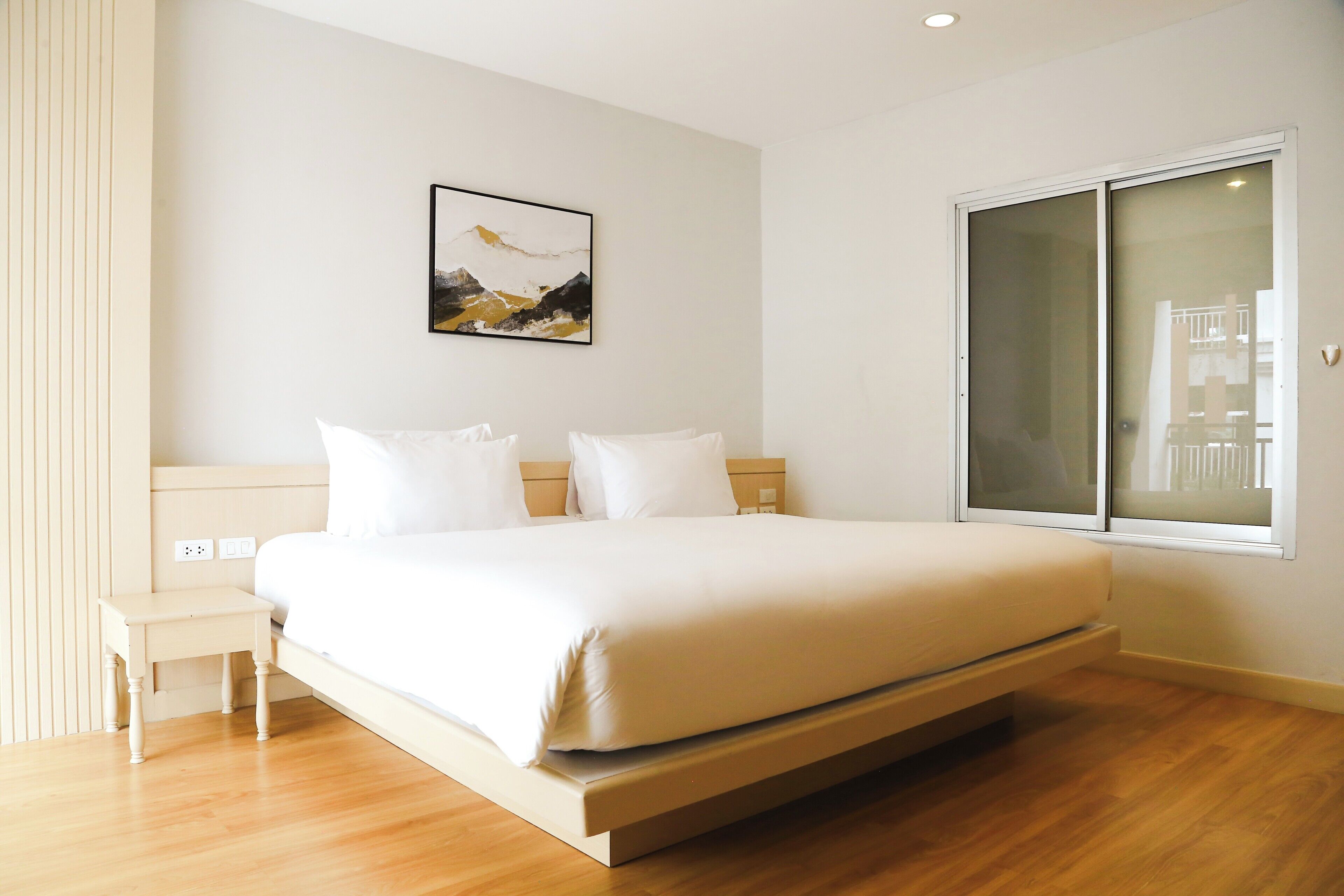 A modern bedroom with a bed, bedside tables, and a large window.
