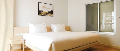 A modern bedroom with a bed, bedside tables, and a large window.