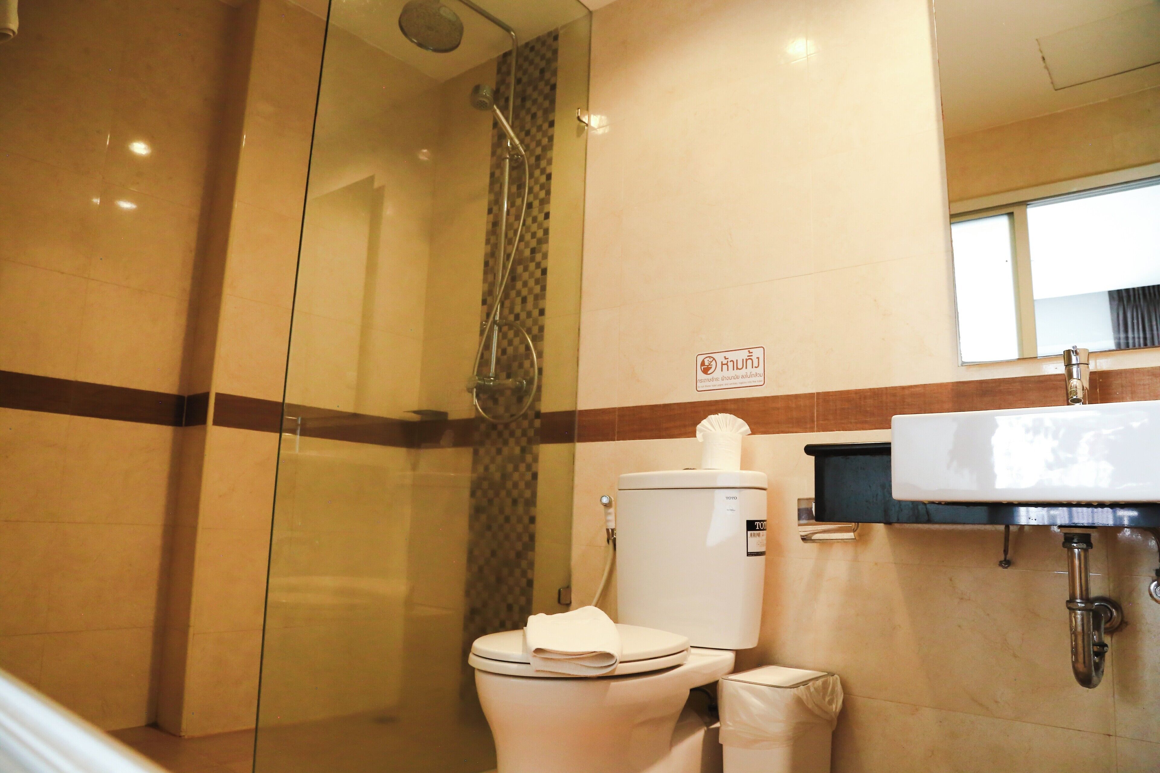 A bathroom with a glass shower enclosure, a toilet, and a sink.