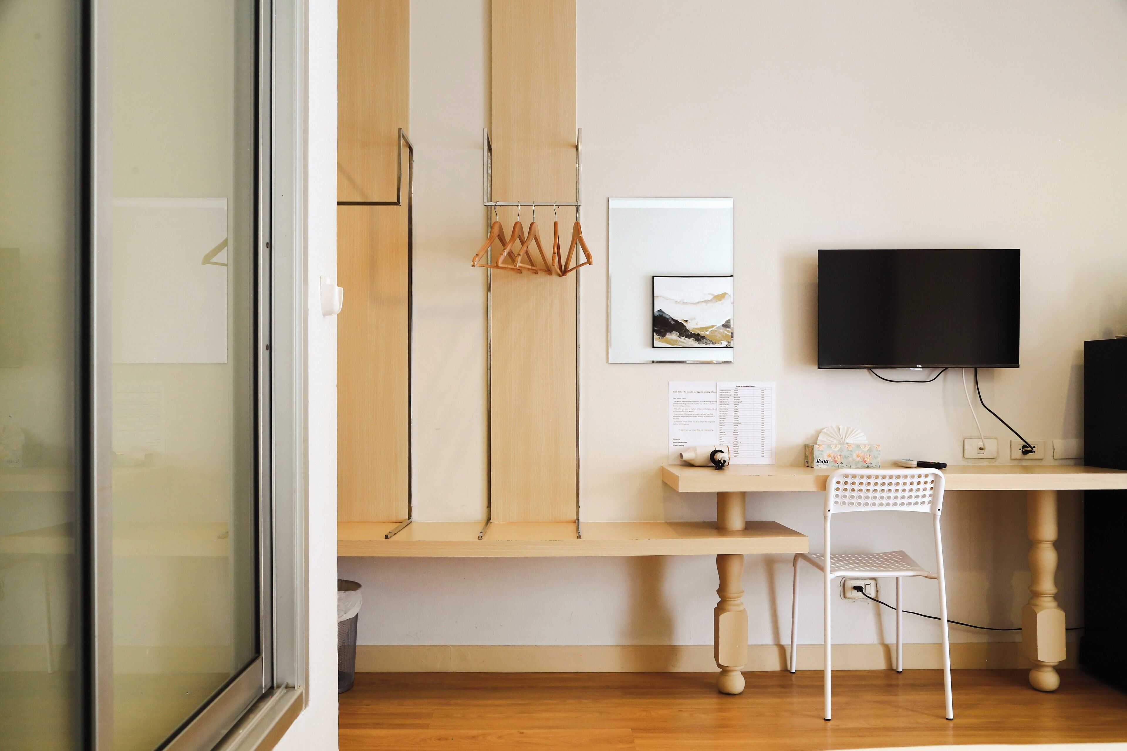 A modern room with a wooden desk, a white chair, a TV, and a framed picture on the wall.