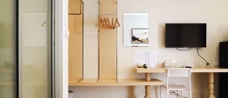 A modern room with a wooden desk, a white chair, a TV, and a framed picture on the wall.