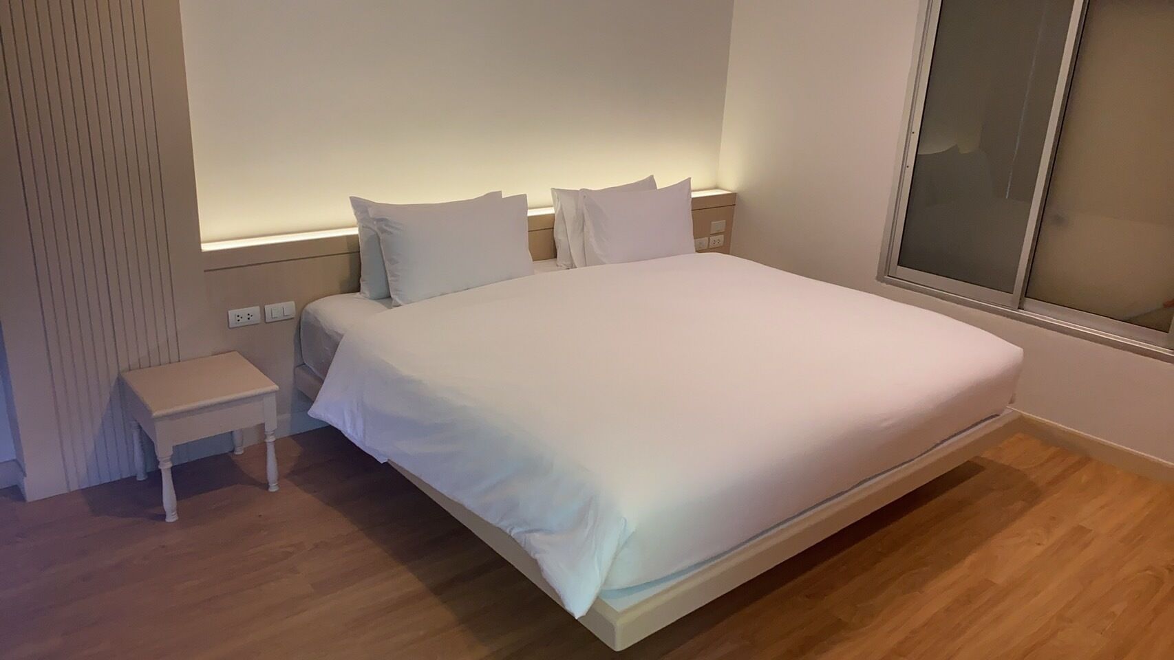 Une chambre à coucher moderne avec un grand lit, une petite table de chevet et une fenêtre.