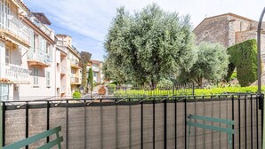 A balcony with a view of a church, a fence, and a row of buildings.