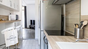 A modern kitchen with a stainless steel refrigerator, a microwave, and a wooden countertop. There is a towel rack with a bag labeled "Cannes Florence Residences".