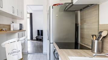 Une cuisine moderne équipée d’un réfrigérateur en acier inoxydable, d’un four à micro-ondes et d’un plan de travail en bois. On y trouve également un porte-serviettes avec un sac étiqueté « Cannes Florence Residences ».
