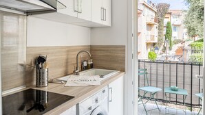 A modern kitchen with a built-in oven, a stainless steel sink, and a compact washing machine.