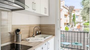 A modern kitchen with a built-in oven, a stainless steel sink, and a compact washing machine.