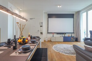 A modern living room with a dining area, a large flat-screen TV, and a cozy seating arrangement.