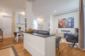 Un espace de vie moderne comprenant un îlot central, un coin repas et un espace détente avec un canapé et un fauteuil.