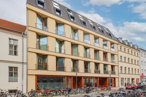 A multi-story building with a row of balconies and a ground-level entrance.