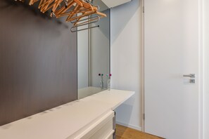 Une salle de bain moderne avec un meuble-lavabo blanc, un miroir et un étendoir à linge en bois.