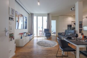A modern living room with a sofa, a dining table, and a large window.