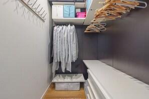 A walk-in closet with a hanging rod, shelves, and a storage bench.