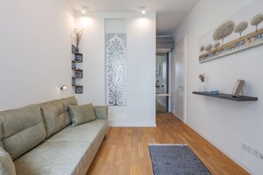 Uma sala de estar moderna com um sofá, um painel decorativo e uma estante com objetos.