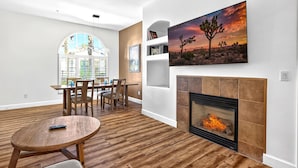 A living room with a fireplace, a dining area, and a large window.