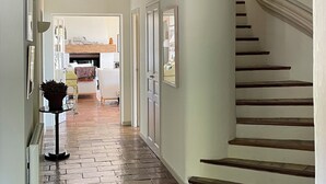 A hallway with a wooden floor, a staircase with wooden steps, and a ceiling with a decorative light fixture. - Villa Bougainvilliers (Vence)