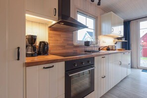 Eine moderne Küche mit weißen Schränken, einer Holz Arbeitsplatte, einem eingebauten Backofen und einer Kaffeemaschine.
